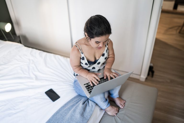 Pessoa com nanismo em casa usando computador