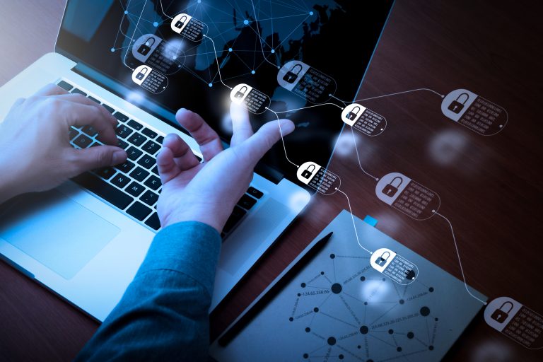 Pessoa mexe num laptop com ícones de cadeado