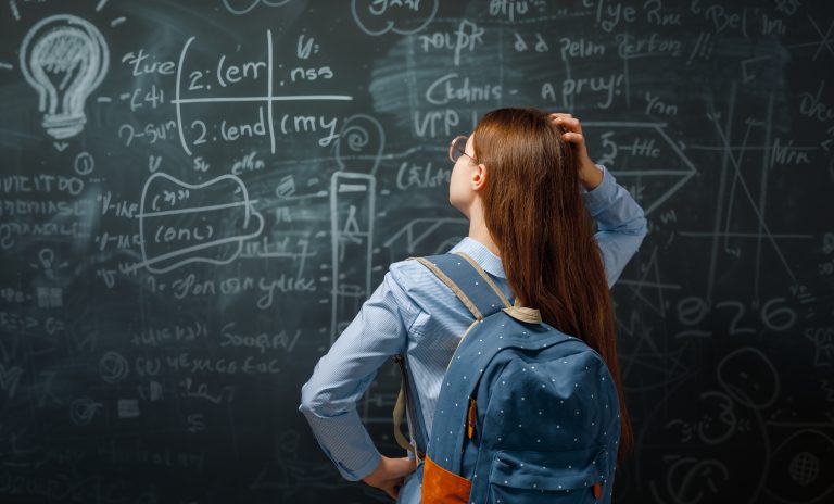 Aluna olha fórmulas escritas num quadro negro