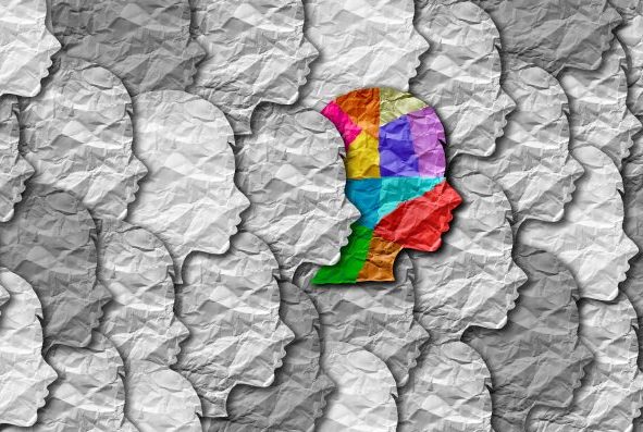 Várias cabeças desenhadas de perfil em cinza e apenas um com cores diversas