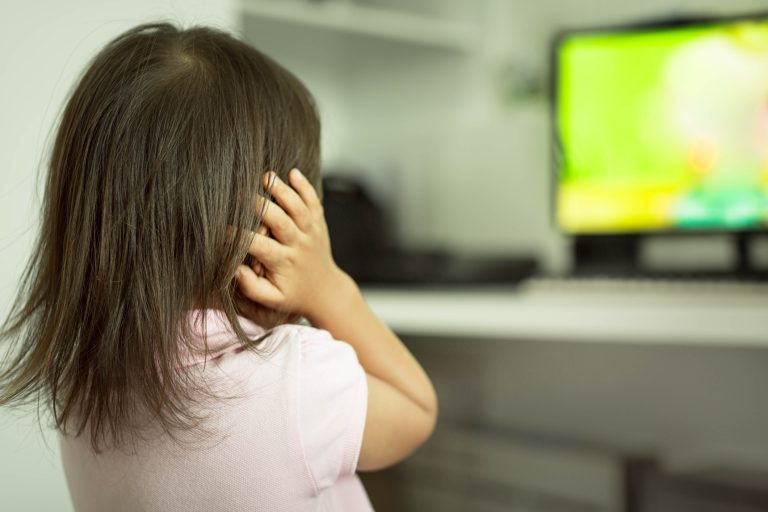 Criança de costas com as mãos no ouvido