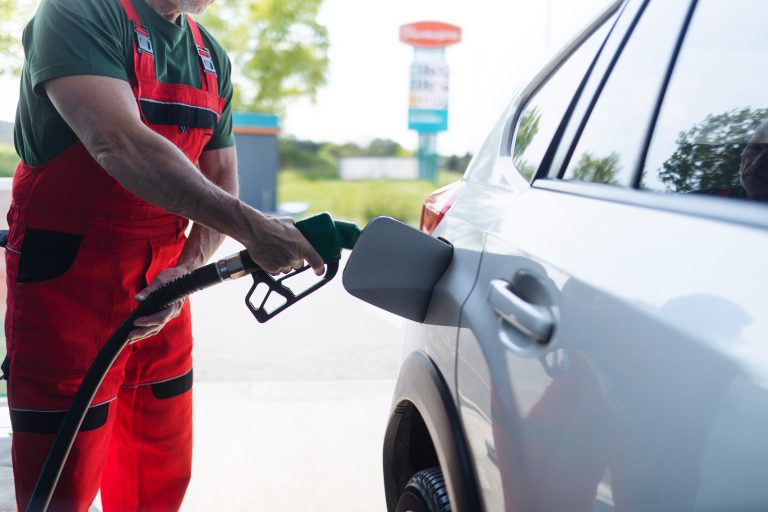 Um frentista abastece o carro num posto de gasolina