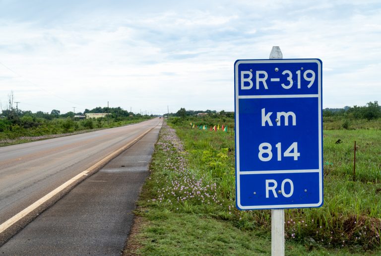 Vista da rodovia BR 319 para o Amazonas e placa de trânsito quilômetro na floresta amazônica, Rondônia, Brasil.