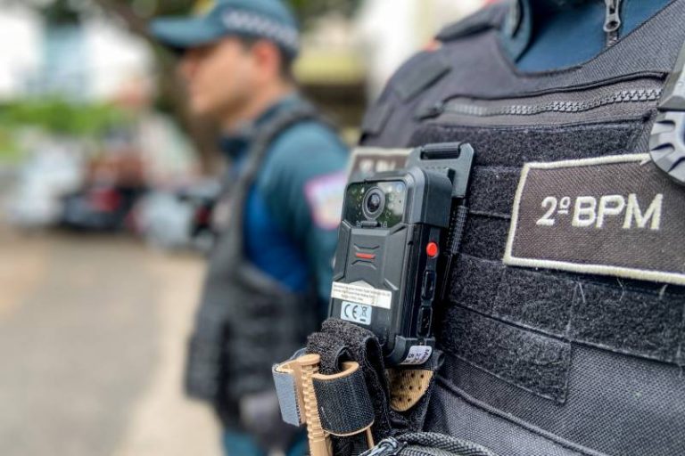 Policiais ao lado de viaturas