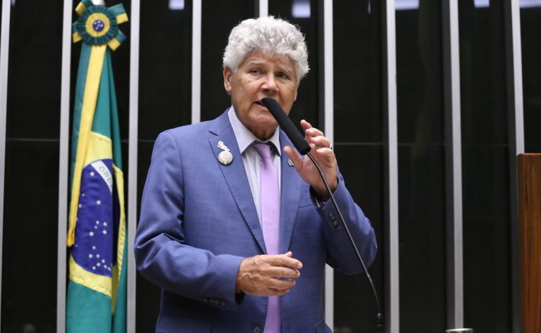 Deputado Chico Alencar fala ao microfone. Ele é claro, tem o cabelo cacheado e grisalho, e usa um terno cinza