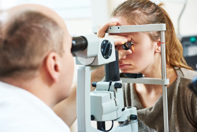 Oftalmologista examina os olhos de uma mulher com um aparelho