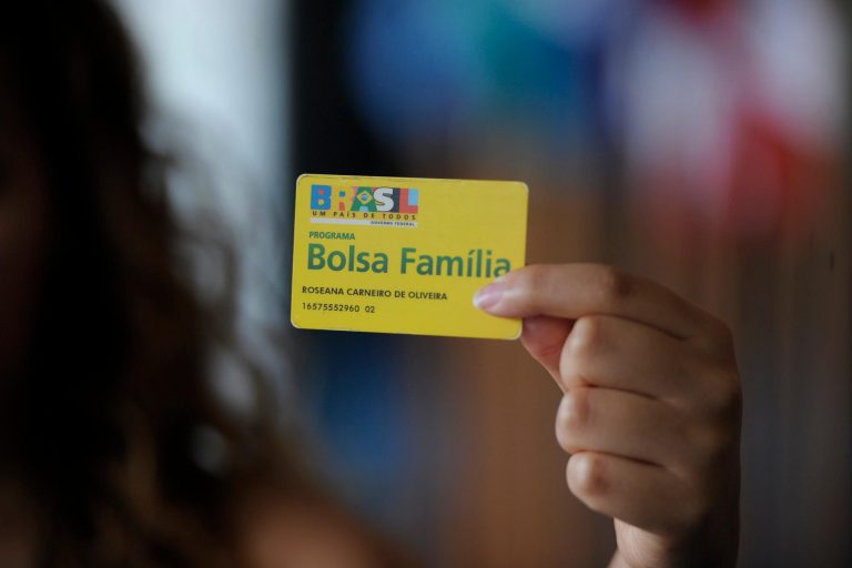 Mulher segura um cartão do Bolsa Família