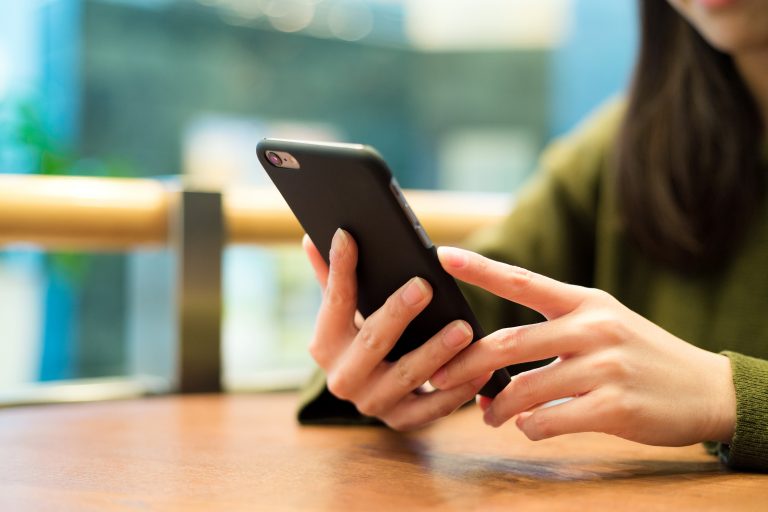 Mulher sentada olhando o celular em sua mão