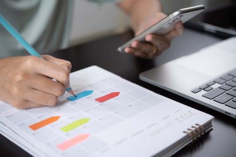 Agenda de programação do organizador de eventos planeja o evento na programação. Mulher de negócios verificando planejador no celular, tomando nota na mesa do calendário na mesa do escritório