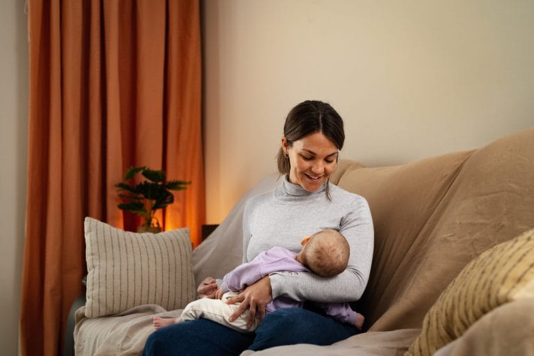 Mãe feliz cuidando de seu pequeno bebê dormindo em seus braços em casa - Conceito de família e maternidade - adoção - cuidado
