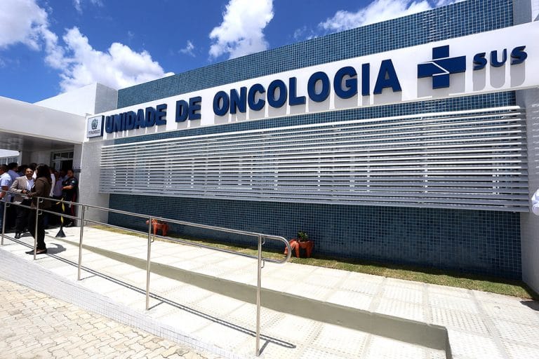 Prédio branco com letreiro azul escrito: unidade de oncologia