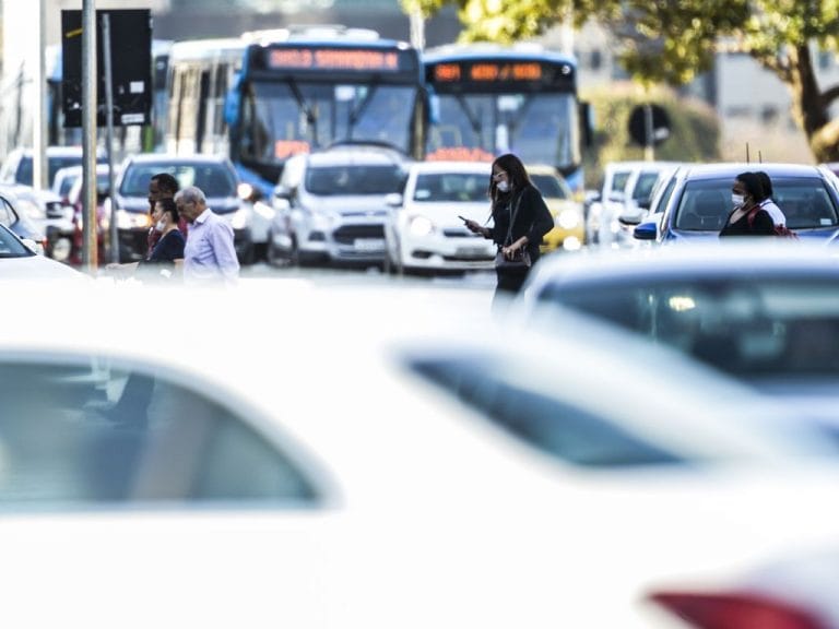 Trânsito intenso de veículos e pessoas atravessando a rua