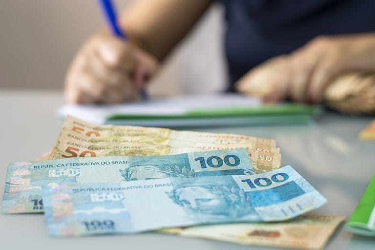 pessoa faz calculo em frente a notas de dinheiro