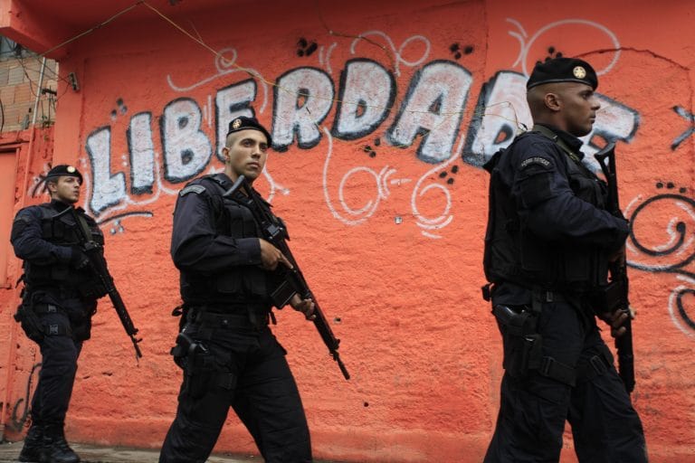 Policiais caminham segurando fuzis