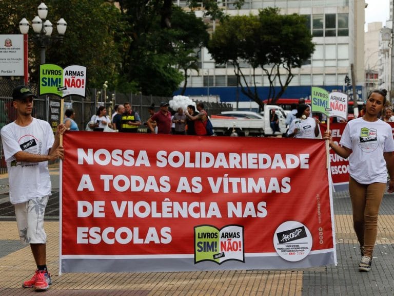 Passeata contra violência escolar. Dois jovens seguram uma faixa pedindo paz