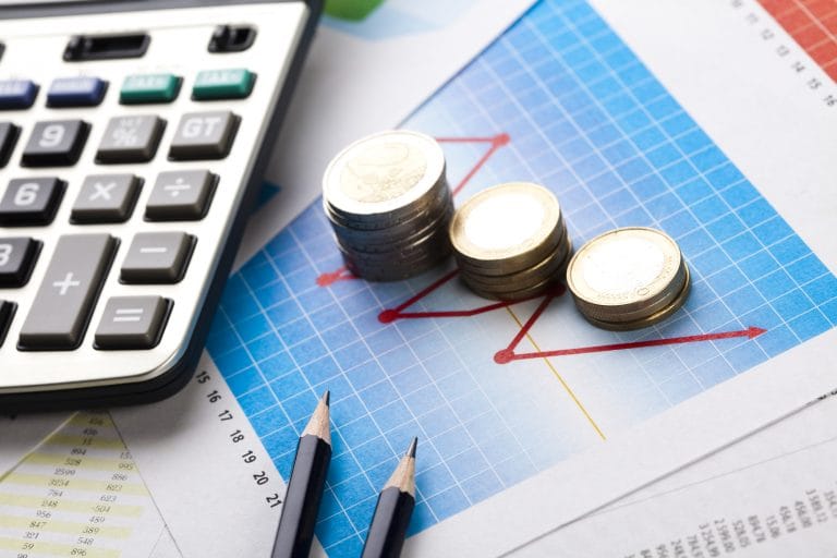 Gráficos com moedas, uma calculadora e um caneta em cima