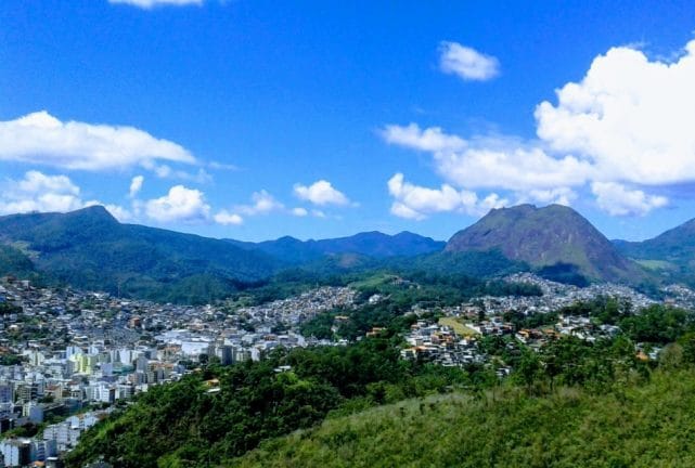 Vista aérea de uma cidade cercada de morros e um céu azul