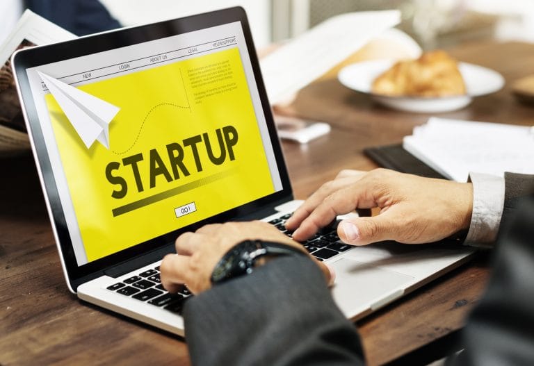 Pessoa digita num laptop onde se lê: startup