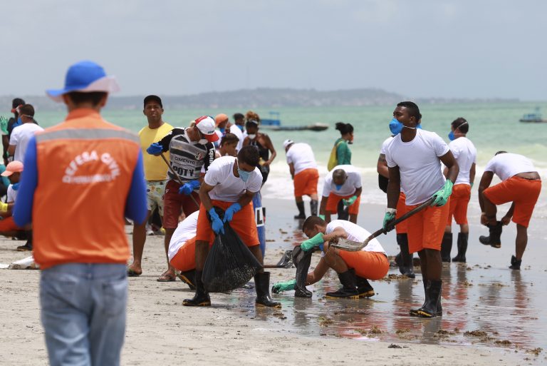 Voluntários recolhem óleo espalhado na areia da praia