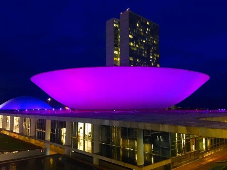 Prédio do Congresso Nacional iluminado de roxo