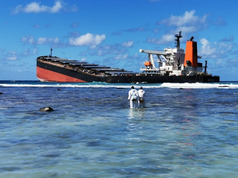 Navio afundando no mar enquanto dois homens olham no raso