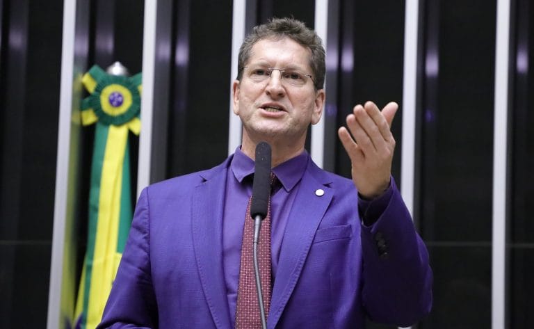 Deputado Jilmar Tatto fala ao microfone. Ele é branco e usa óculos, terno azul-marinho e gravata vermelha