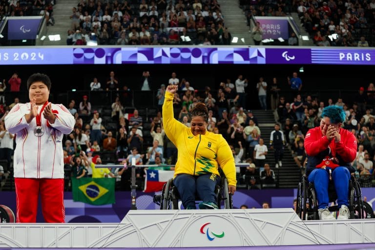 Uma atleta em cadeira de rodas está no pódio em 1º lugar