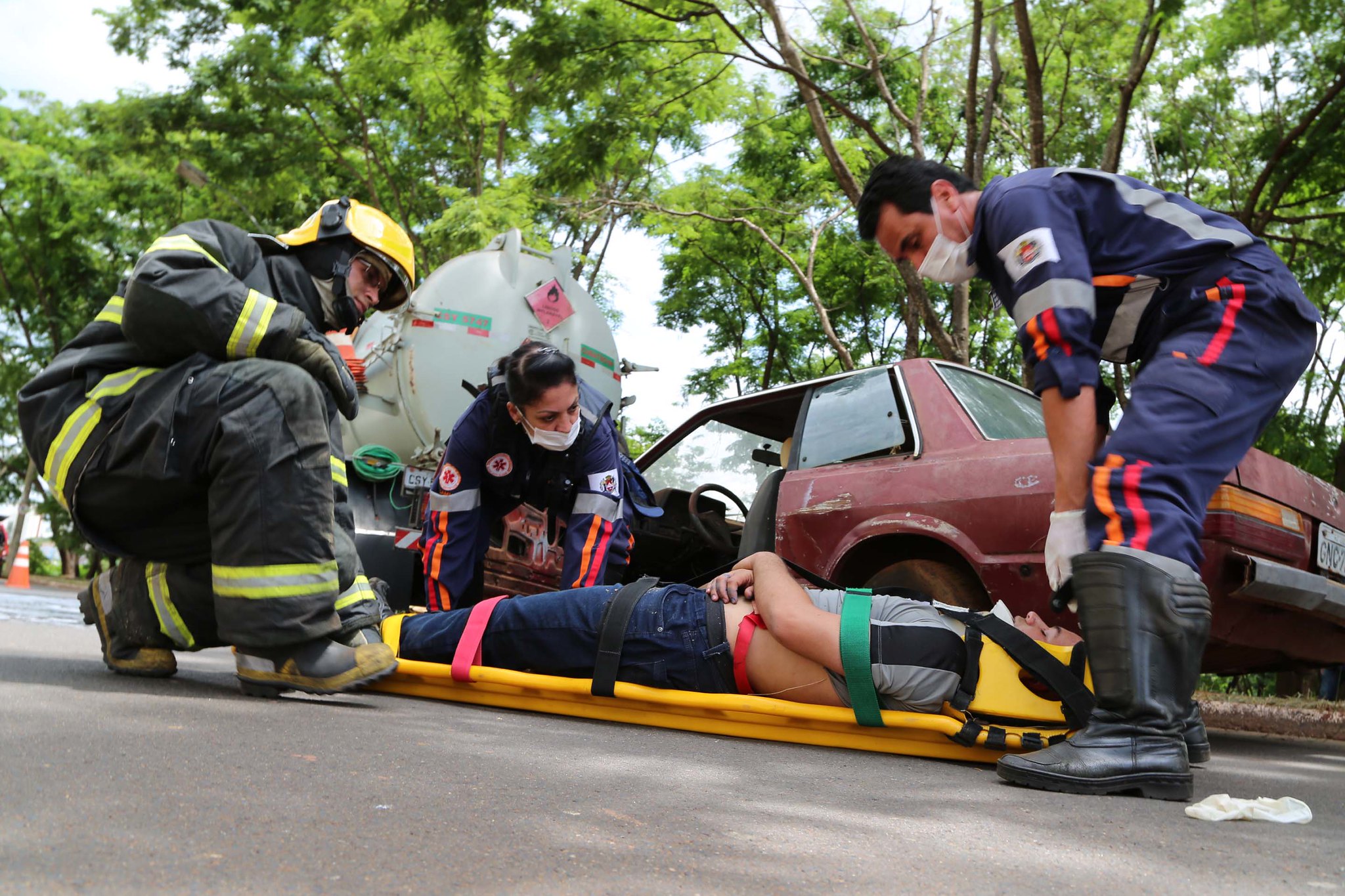 Uma pessoa está deitada numa maca sendo socorrida depois de um acidente de carro