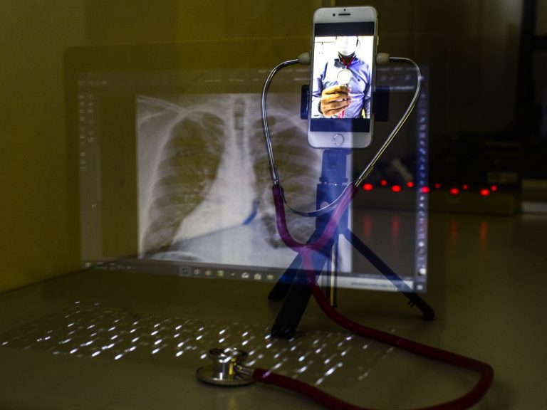 Um computador com a imagem de um pulmão, um estoscópio e um celular com a imagem de um médico