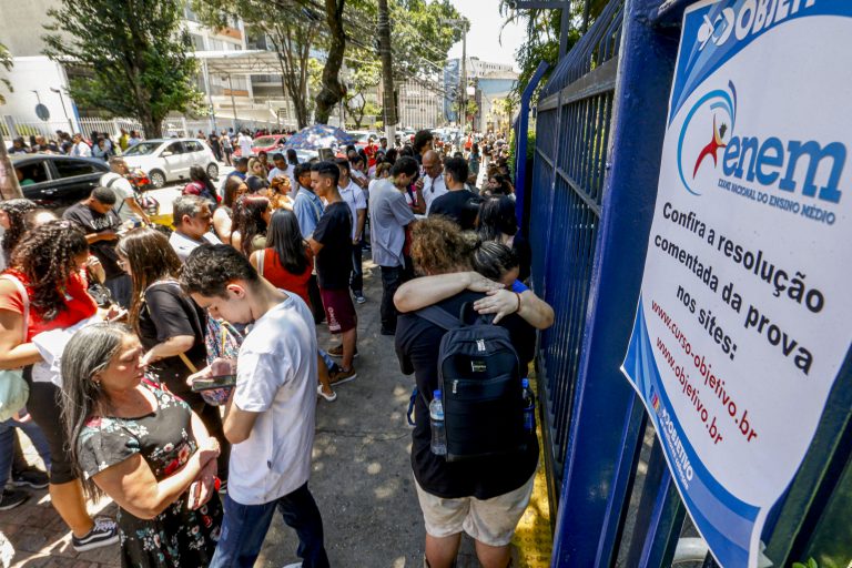 Estudantes aguardam na frente de um portão para fazer o Enem