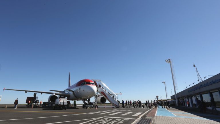 Aeroporto com avião parado e passageiros embarcando