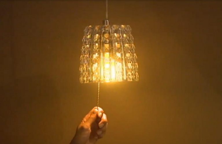 Uma pessoa segura a corda de uma luminária acesa