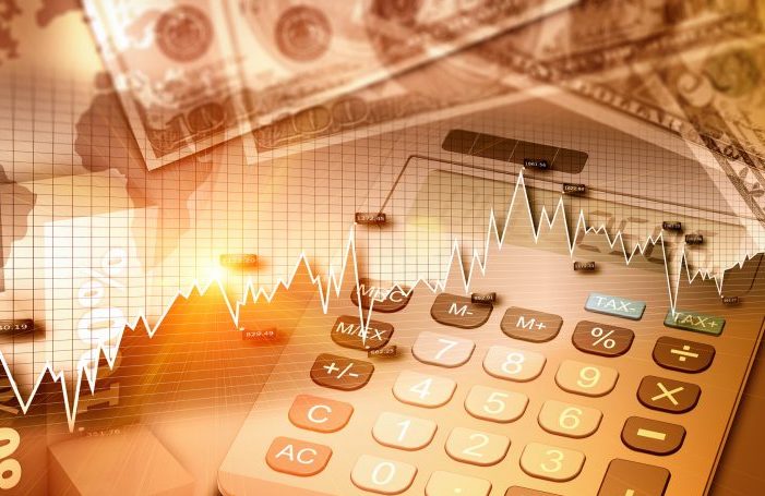 Imagem de uma calculadora com notas de dinheiro e gráficos em cima