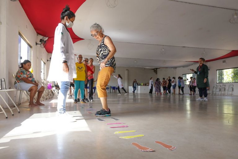 Pessoas idosas fazem exercícios para melhorar o equilíbrio acompanhadas de profissional da saúde